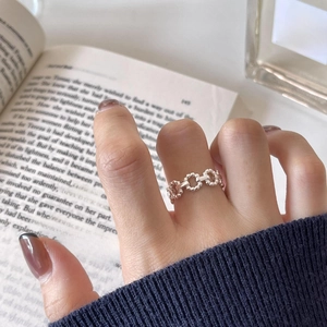 Close-up of a 925 sterling silver hollow chain ring worn on a finger over a book