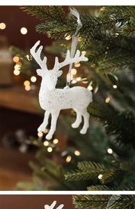 Détail d'un renne de Noël blanc pailleté suspendu à une branche de sapin de Noël