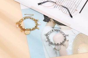 Detail of double-layer titanium steel bracelet featuring Hamsa pendant and white pearl charm
