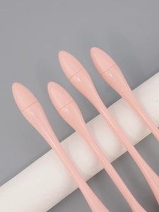 Close-up of four pink makeup brushes with streamlined handles resting on a white stand