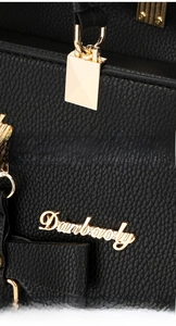 Close-up of black lychee grain leather texture and glossy golden metal buckle on handbag