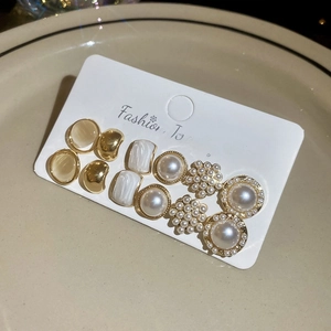 Detail of 6-pair gold earring set with faux pearls and opals on display card