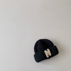 Close-up of black knit beanie for kids showing detailed texture and N letter patch detail