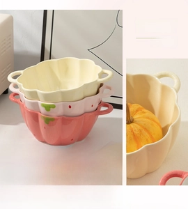 Close-up of ceramic pumpkin bowls with petal edges and strawberry detail in warm tones