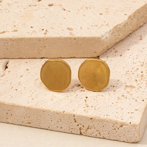 Detailed macro view of gold matte geometric octagonal stud earrings on stone