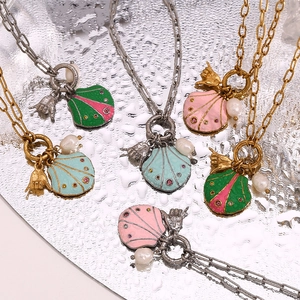 Detailed view of 18K gold plated shell pendants with colorful enamel on a water mirror