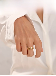 Close-up of golden Cuban chain ring worn by a model in a minimalist style setting