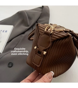 Close-up of the pleated texture and fine stitching on a brown leather handbag with gold hardware