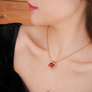 Detail of a gold snake chain necklace featuring a vintage red square gemstone pendant