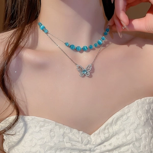 Close-up of double-layered silver necklace with blue cat eye beads and zircon butterfly