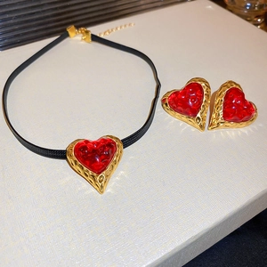 Detailed macro view of vintage red heart jewelry set with gold textured metal edges