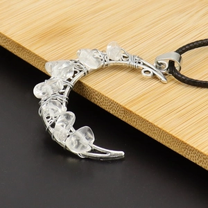 Macro view of crescent moon pendant with silver wire-wrapped clear crystals and cord