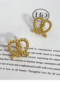 Macro detail of gold twisted rope knot stud earrings with a high-polished metallic finish