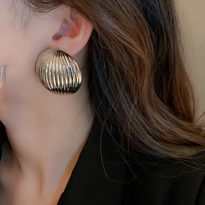 Detailed close-up of chunky silver striped hoop earrings with mirror finish on a model