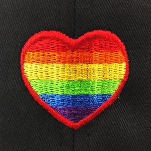 Macro view of rainbow heart embroidery patch with detailed stitching on black twill