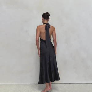 Detail view of the elegant halter neck ribbons and open back on a black satin maxi dress