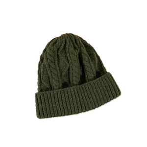 Detail view of dark green knit beanie showing thick cable stitch and ribbed cuff texture