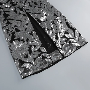 Détail d'une robe de soirée à fente haute avec broderie florale de paillettes argentées