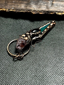 Detail of handcrafted copper wire pendant with amethyst and obsidian on vintage background