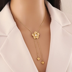 Golden camellia and pearl Y-necklace with heart tassels on elegant beige blazer model