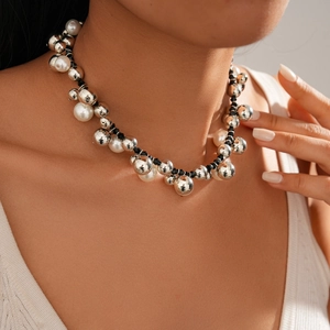 Close-up of a layered necklace with silver beads and white pearls worn by a model