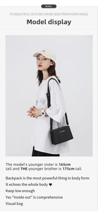 Detail of black leather crossbody bag with white COME KNOWS lettering worn by a model