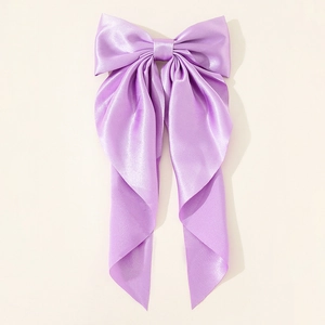 Close-up of the purple satin texture and elegant drape of the oversized bow hair clip
