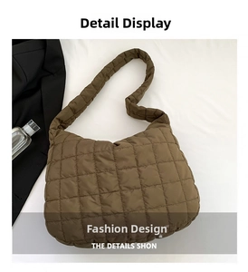 Detailed close-up of brown quilted shoulder bag with wide strap on white background
