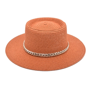 Detail of brick red boater hat with fine straw texture and silver metal chain band