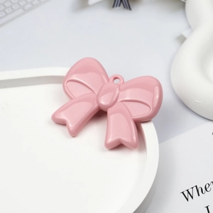 Macro shot of pink acrylic bow pendant with hanging hole for DIY jewelry making
