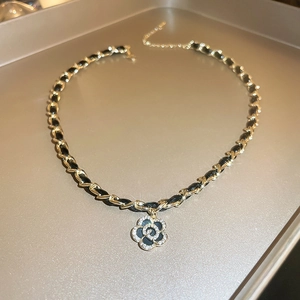 Close-up of camellia pendant with gold-plated leather chain and inlaid cubic zirconia
