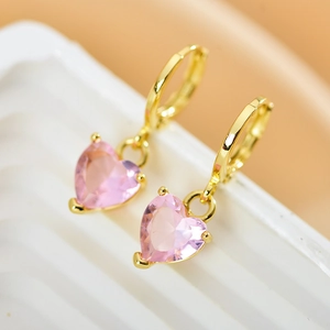 Macro shot of gold hoop earrings featuring sparkling pink heart-shaped zircon stones