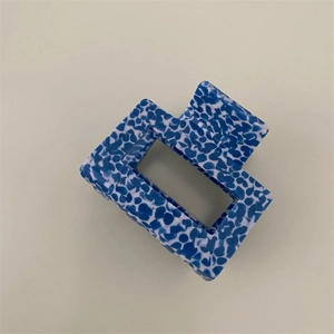 Close-up of a blue and white speckled rectangular hollow hair claw clip with spring mechanism