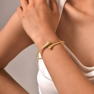Close-up of minimalist gold teardrop open cuff bracelet worn by a model on wrist