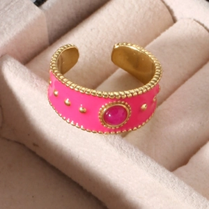 Macro shot of wide gold-plated ring with rose pink enamel and inlaid natural stone