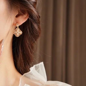 Gros plan de boucles d'oreilles fleur dorées avec perles et petits diamants