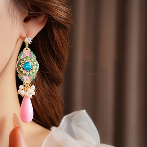 Détail de boucles d'oreilles vintage avec gemmes bleues et perles roses pendantes