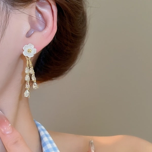 Close-up of elegant flower tassel earrings with crystals worn by a model in warm light