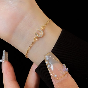 Détail d'un bracelet en chaîne dorée avec un pendentif fer à cheval serti de zircons