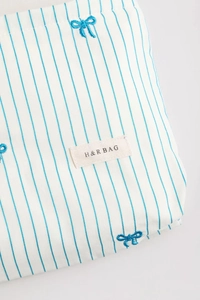 Close-up of blue stripe fabric with embroidered bows and H & R BAG woven label