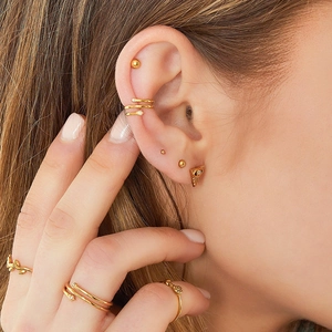 Close-up of golden ear cuff and star-shaped zircon stud on a model with matching rings