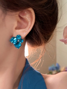 Close-up of blue geometric faceted crystal flower earring on model left ear