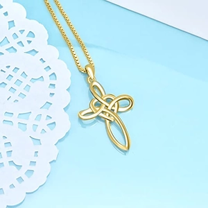 Macro shot of gold Celtic cross pendant with box chain on elegant lace background