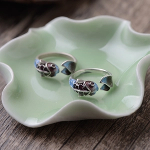 Detailed view of Koi fish enamel rings with gradient scales on a decorative ceramic plate