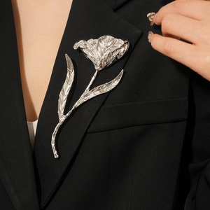Detailed view of silver tulip flower brooch on a black suit lapel with metallic luster