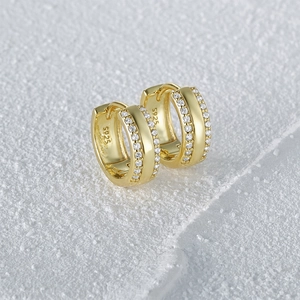Close-up of S925 sterling silver stamp and sparkling cubic zirconia on gold hoop earrings