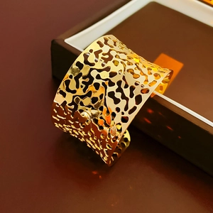 Macro detail of gold irregular hollow cuff bracelet resting on a luxury jewelry box