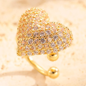 Macro side view of golden heart-shaped ear cuff with pave-set clear zircon stones