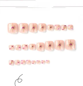 Detail of pink press-on toenails featuring gold sunburst and purple heart patterns