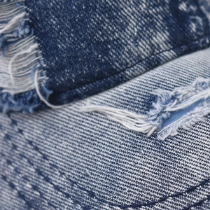 Distressed blue denim baseball cap with vintage wash and ripped frayed hole details